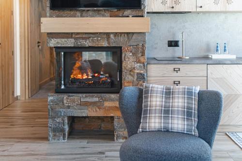 a living room with a fireplace and a chair at Pensjonat Orlik Mountain Resort&SPA in Bukowina Tatrzańska