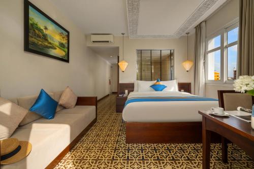 a hotel room with a bed and a couch at Royal Riverside Hoi An Hotel & Spa in Hoi An