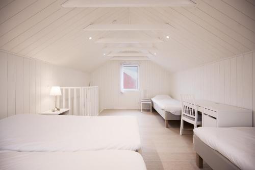 a white room with two beds and a desk at Haludden in Stora Dyrön