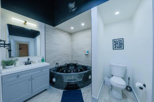 a bathroom with a black tub next to a toilet at McCormick 6Br-4Ba Luxury Suite that sleeps 12 guests with Jacuzzi & Pool table, Group stay and Optional parking in Chicago