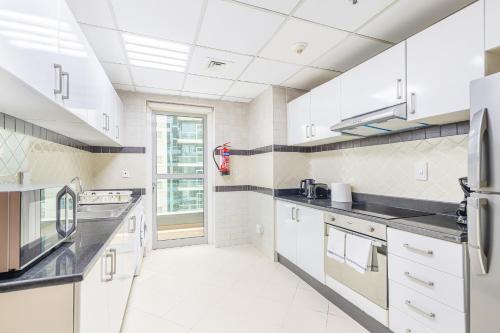 a large kitchen with white cabinets and black counter tops at Elegant 3BR in JBR w/ partial Marina View in Dubai