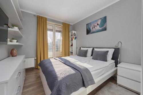 a white bedroom with a large bed and a window at Apartament Krzycka Wrocław by Renters in Wrocław