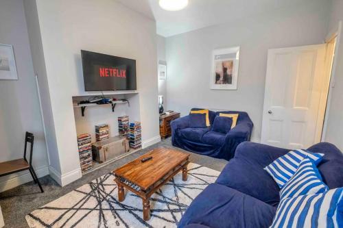 a living room with two blue couches and a coffee table at Beautiful Apartment with Parking in Hexham
