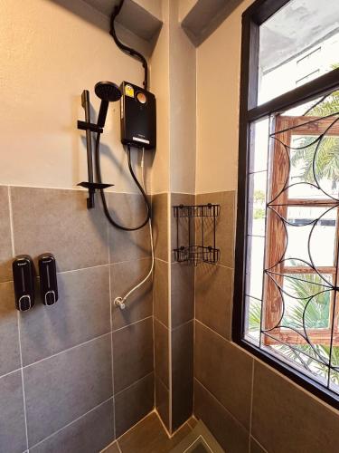 bagno con doccia e asciugacapelli appeso al muro di Hostel Friends Station & Cafe a Pattaya Sud