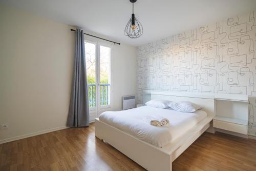 een witte slaapkamer met een bed en een raam bij Santa Monica, maison spacieuse Reims Cormontreuil in Cormontreuil