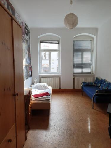 ein Wohnzimmer mit einem blauen Sofa und 2 Fenstern in der Unterkunft Kulturschutzgebiet in Dresden