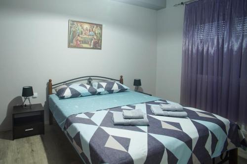 Schlafzimmer mit einem Bett mit einer blauen und weißen Bettdecke in der Unterkunft Apartmani 18-ka in Gevgelija