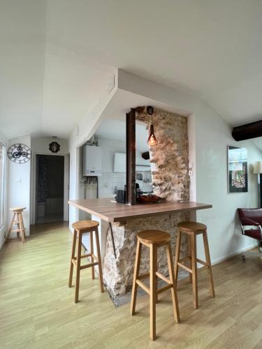 une cuisine avec un comptoir et des tabourets dans une pièce dans l'établissement Le Central Victoria VI, à Nancy