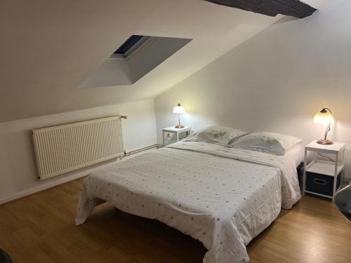 Un dormitorio blanco con una cama y dos mesitas de noche. en Le Central Victoria VI, en Nancy