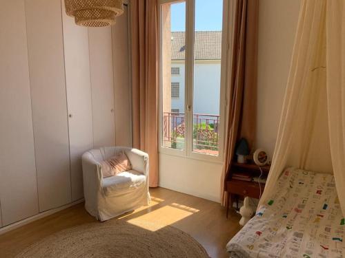 - une chambre avec une chaise blanche et une fenêtre dans l'établissement Superbe meulière familiale, à Rosny-sous-Bois