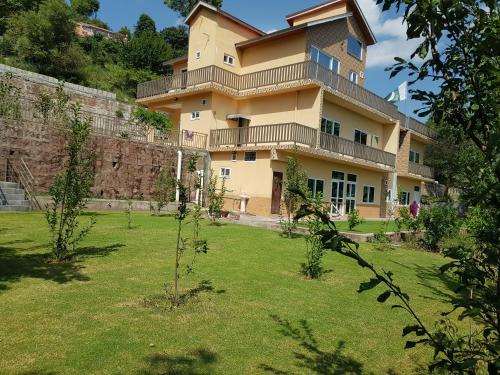 a large building with a lawn in front of it at Roof Top Resort in Murree