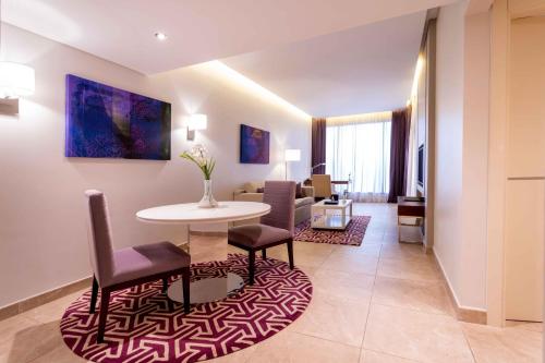 a living room with a table and chairs at Mercure Dubai Barsha Heights Hotel Suites And Apartments in Dubai