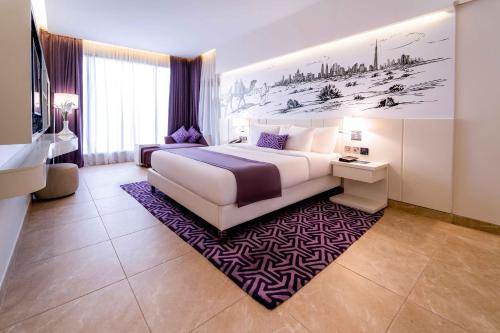 a bedroom with a large white bed and a purple rug at Mercure Dubai Barsha Heights Hotel Suites And Apartments in Dubai