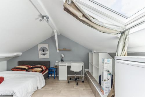 een slaapkamer op zolder met een bed en een bureau bij Appartement au calme et proche des transports in Créteil