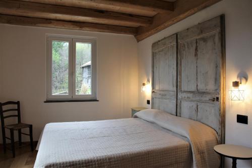 1 dormitorio con cama blanca y ventana en La Pezzuola 53, en Sopralacroce