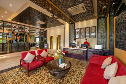 a lobby of a hotel with red chairs and a counter at Royal Riverside Hoi An Hotel & Spa in Hoi An
