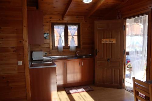 a kitchen in a log cabin with a sink and a door at Cabañas Caudiel in Caudiel