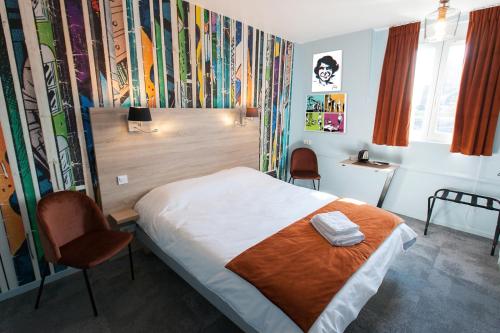 ein Hotelzimmer mit einem Bett und Stühlen in der Unterkunft Logis - Hostellerie & Restaurant du Marché in Le Cateau