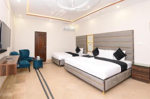 a hotel room with two beds and a desk and a television at Hotel Five Season Lahore in Lahore