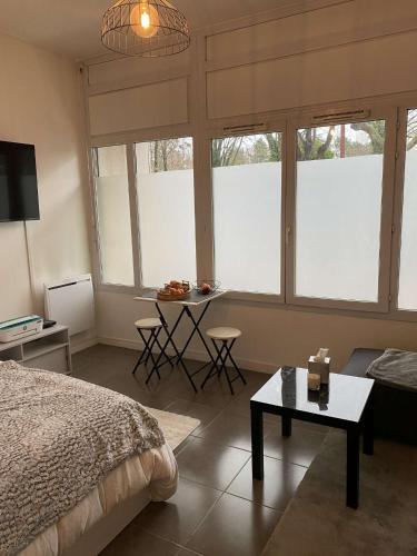 1 dormitorio con cama, mesa y ventanas en Studio Porte de Paris 15e, en Issy-les-Moulineaux