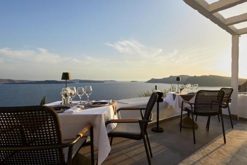a table and chairs on a patio with a view of the water at Filotera Suites in Oia
