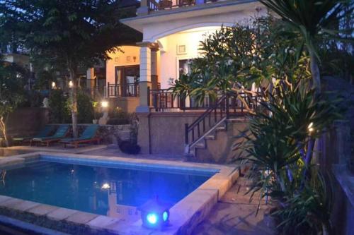 a swimming pool in front of a house at night at Acarya Bungalows in Ambat