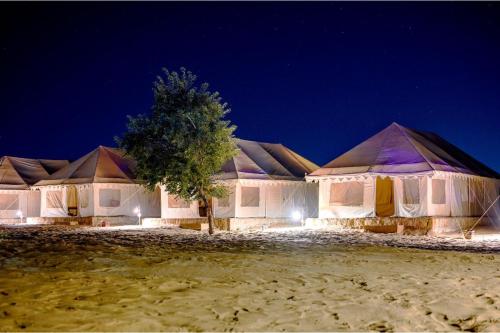 a row of white tents with a tree at night at Prince Desert Camp in Sām