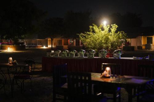 a patio with tables and chairs at night at Prince Desert Camp in Sām
