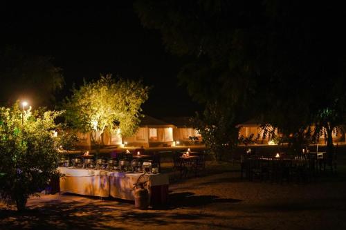 a patio with tables and chairs at night at Prince Desert Camp in Sām