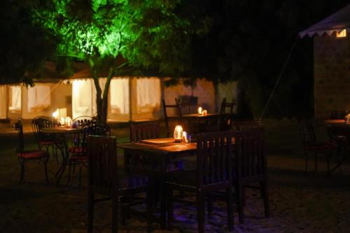 an outdoor restaurant with tables and chairs at night at Prince Desert Camp in Sām