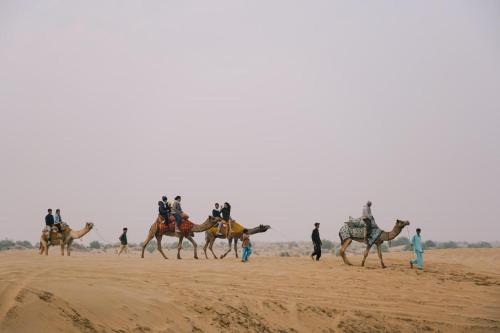 a group of people riding on camels in the desert at Prince Desert Camp in Sām