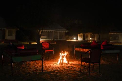a fire in the sand at night with chairs and tables at Prince Desert Camp in Sām