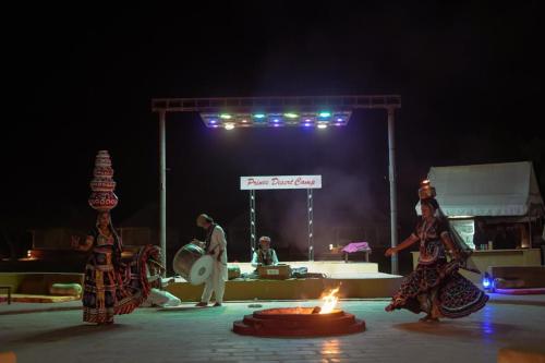 a group of people on a stage with a fire at Prince Desert Camp in Sām