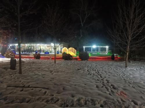 a snow covered park at night with a building in the background at Gabala Bliss Inn Hotel and Restaurant in Gabala