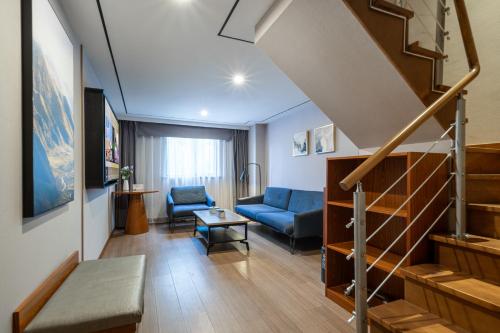 a living room with a blue couch and stairs at Atour X Hotel Shanghai Lujiazui Binjiang Avenue in Shanghai