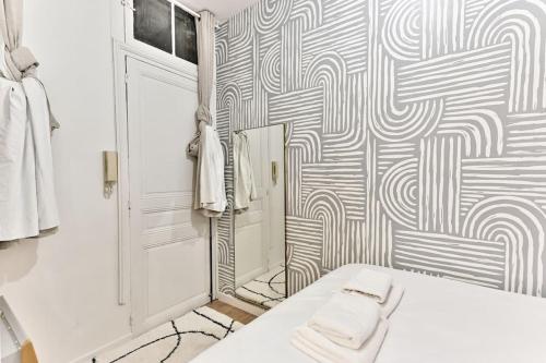 La salle de bains est pourvue d'un lit blanc et d'un mur à motifs. dans l'établissement Appartement central proche Atelier des lumières, à Paris