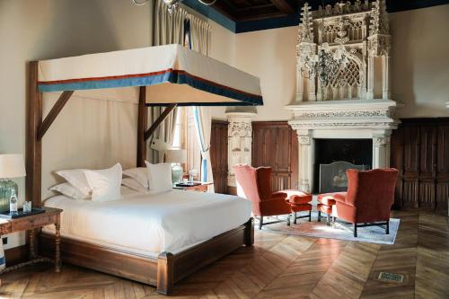a bedroom with a bed and two chairs and a fireplace at Château Sainte Sabine in Sainte-Sabine