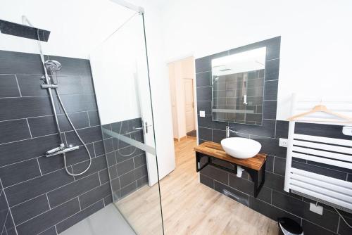 a bathroom with a glass shower and a sink at Logis - Hostellerie & Restaurant du Marché in Le Cateau