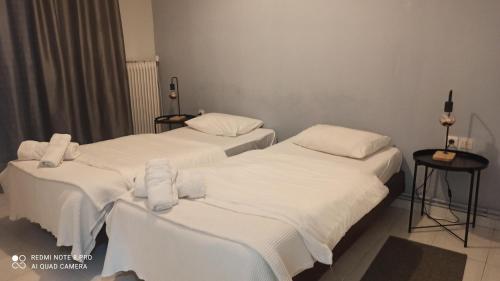 two beds in a room with white sheets and towels at Thess Rooms Agion Panton 12 in Thessaloniki