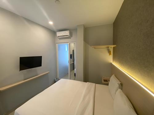 een kleine kamer met een bed en een televisie bij Swasana Hotel Medan in Medan