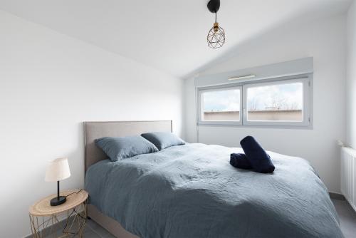 une chambre blanche avec un grand lit avec des draps bleus dans l'établissement Spacieux T4 proche centre-ville, Clim et Parking, à Toulouse