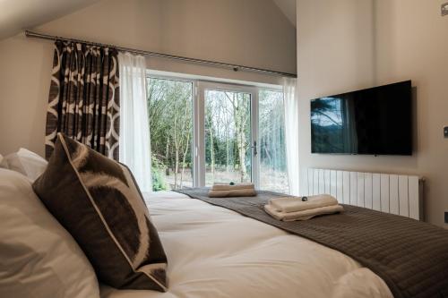 a bedroom with a large bed with two towels on it at Bramley Brook Cottage 5* Luxury in Whalley