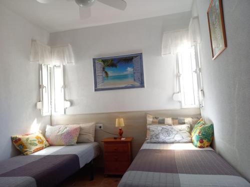 duas camas num quarto com duas janelas em Beach house near Tennis Club La Barrosa em Chiclana de la Frontera