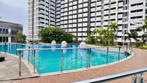 uma grande piscina em frente a um edifício alto em West Vista Apartment JKT Modern Design w/55” TV and 40/mbps Wi-fi em Jakarta
