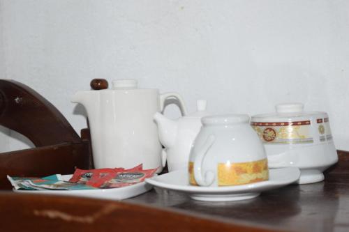 einen Tisch mit zwei weißen Teekesseln und einem Teller in der Unterkunft Pedro home stay in Nuwara Eliya