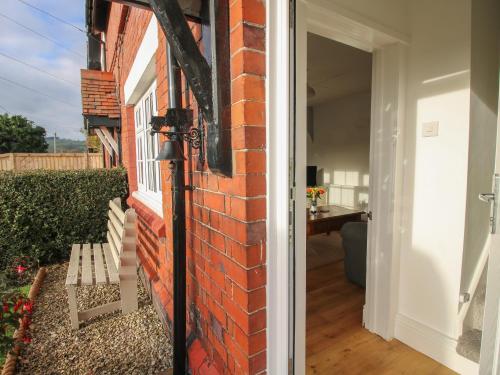 an open door to a brick house with a bench at 8 New Houses in Wrexham