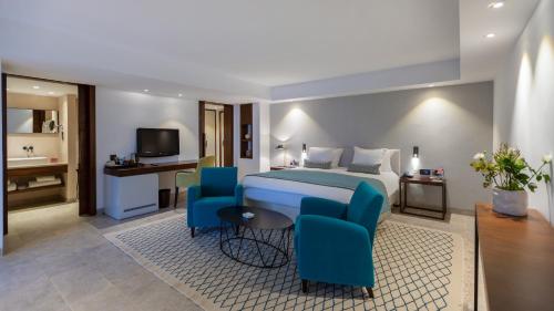 a hotel room with a bed and chairs and a bathroom at Mövenpick Hotel Gammarth Tunis in Gammarth