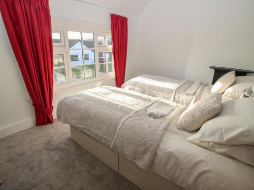 a bedroom with two beds and a window with red curtains at 8 New Houses in Wrexham