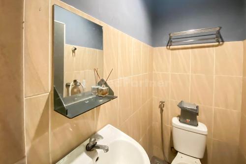 a bathroom with a toilet and a sink and a mirror at Mandala Residence RedPartner in Pulauberayan Dadap