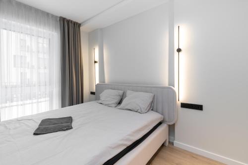 1 dormitorio con 1 cama con sábanas blancas y ventana en Hygge Sand Apartment en Vilna